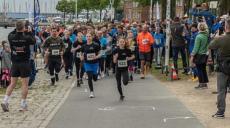 Der Start eines Laufs (2024 Hospizlauf), vorn ein junges Mädchen, hinten die Hafenkulisse